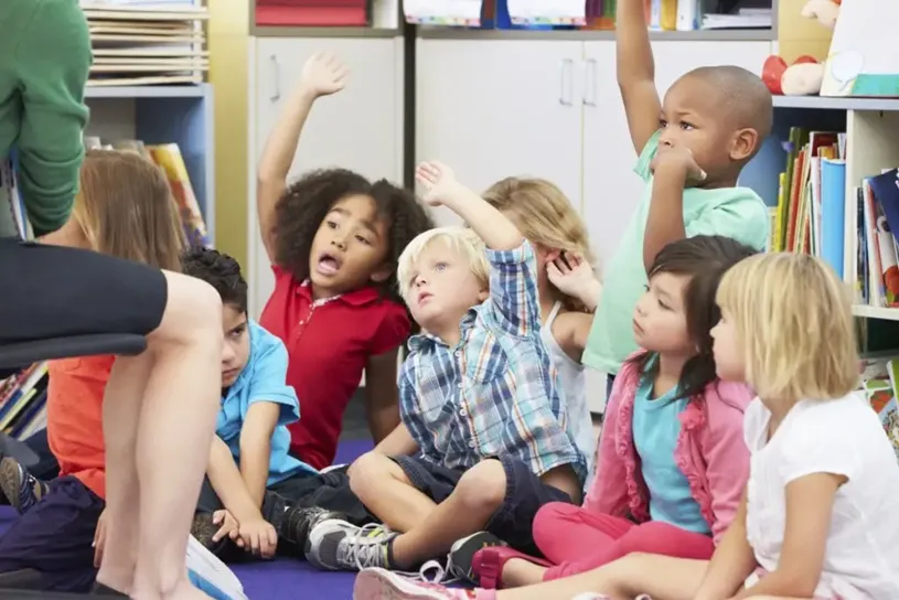 Kids in a circle raising their hand eagerly