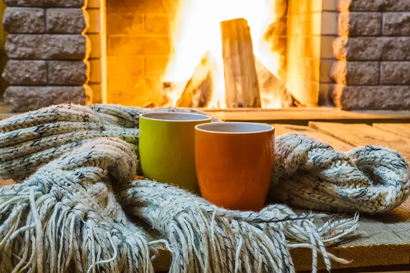 two cups of cocoa in front of a fireplace