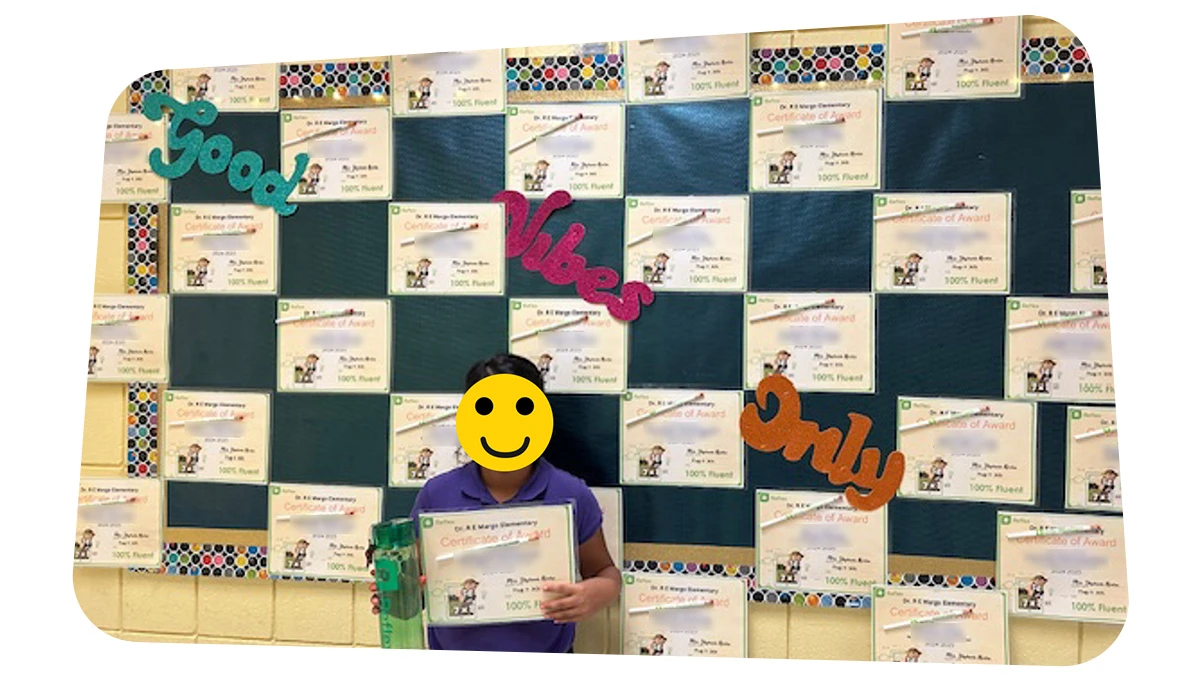 Student in front of bulletin board with and holding a certificate