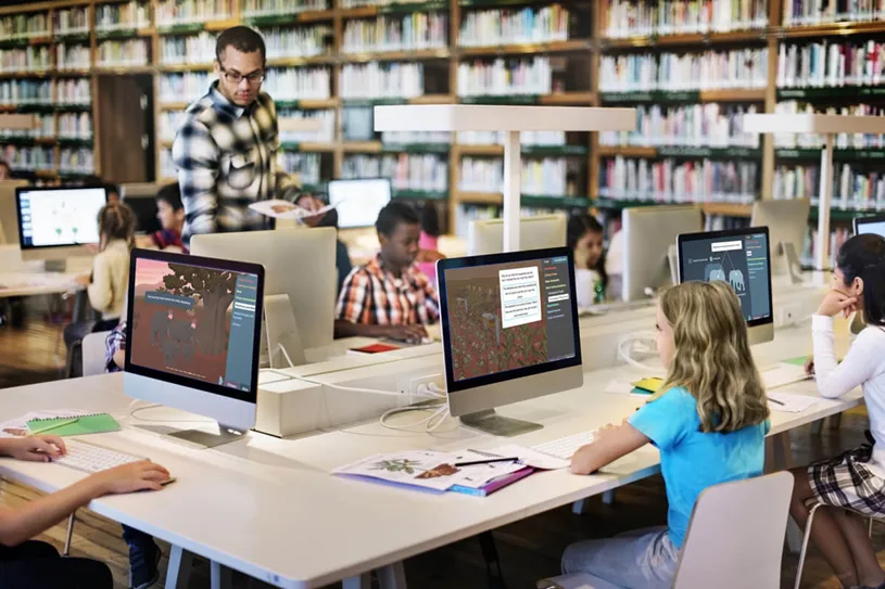 Teacher monitoring students working in a computer...