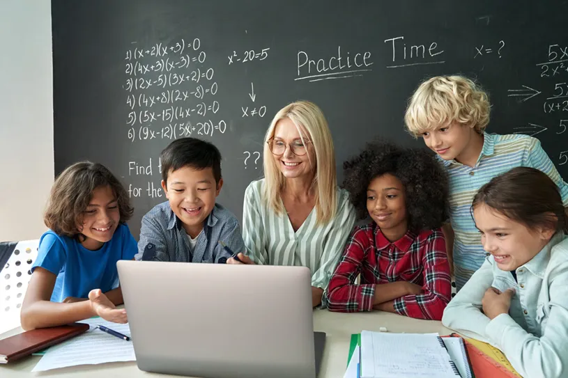 Group of diverse students sit at a table with a...