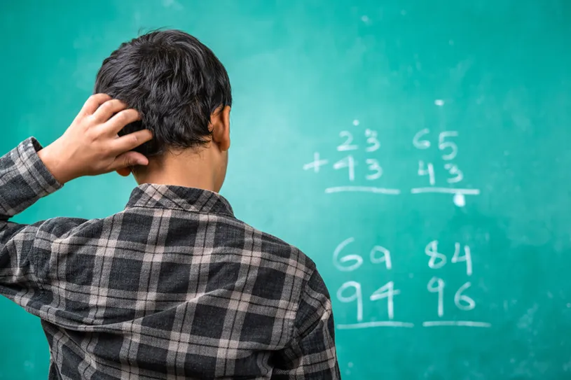 Boy looking at chalkboard confused at a math...