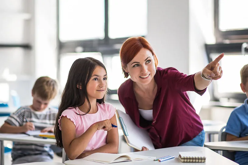 a teacher pointing at the whiteboard explaining...
