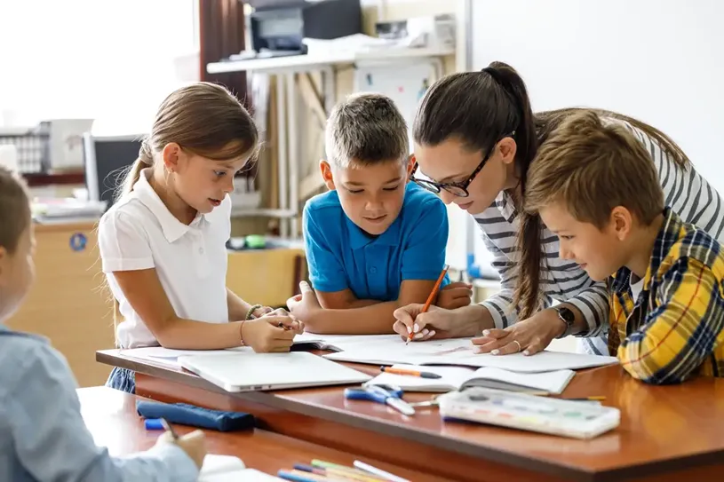 Female teacher helps school kids to finish they...