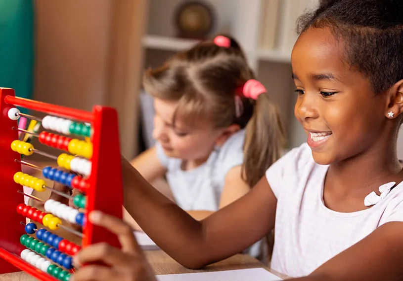 Two young female students working with an abacus