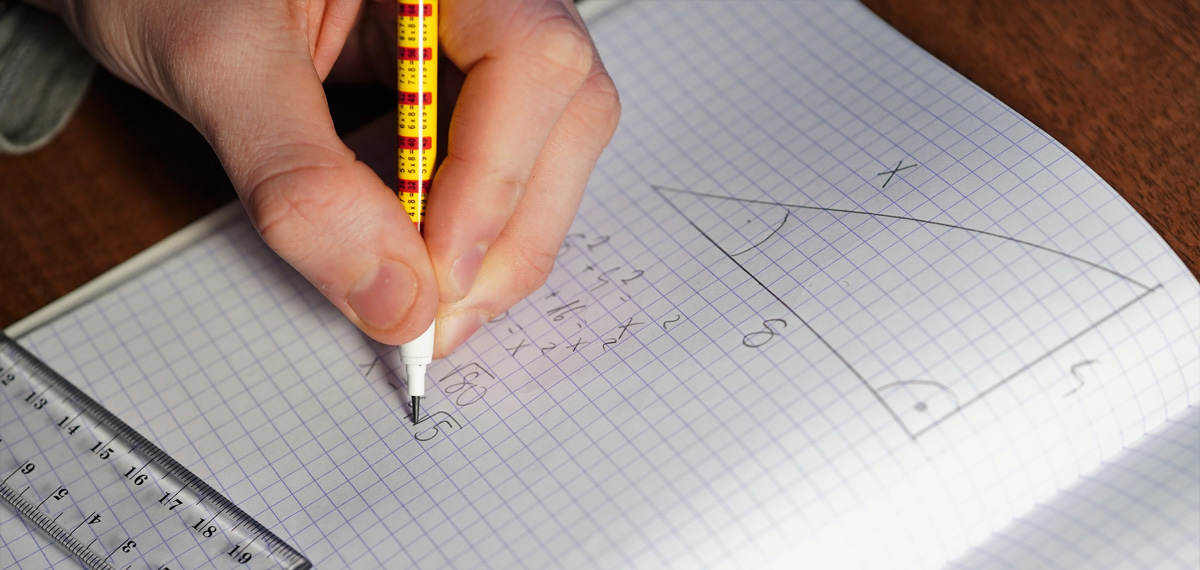 A student is holding a pencil and writing down calculations