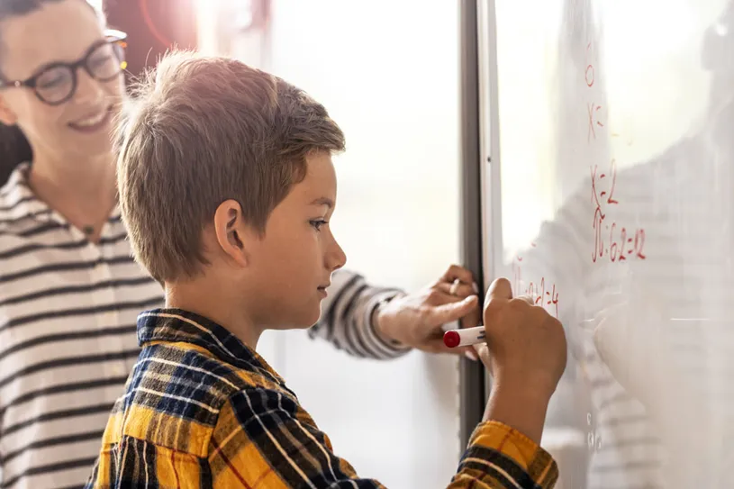 Boy calculating math at the white board. He is...
