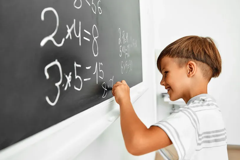 Kid learning math facts at the black board.