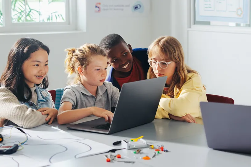 Four students working together on a laptop...