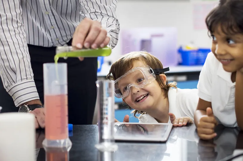 Young student wearing safety goggles and...
