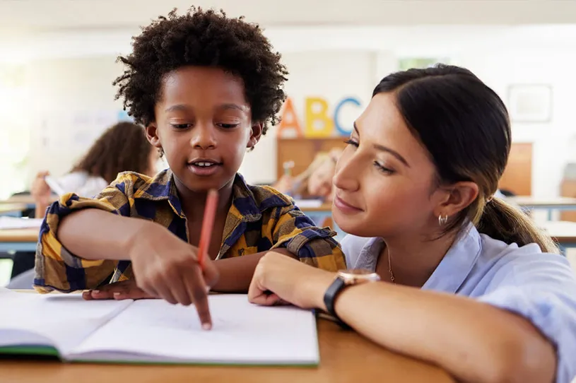 Young student working with a female teacher at a...