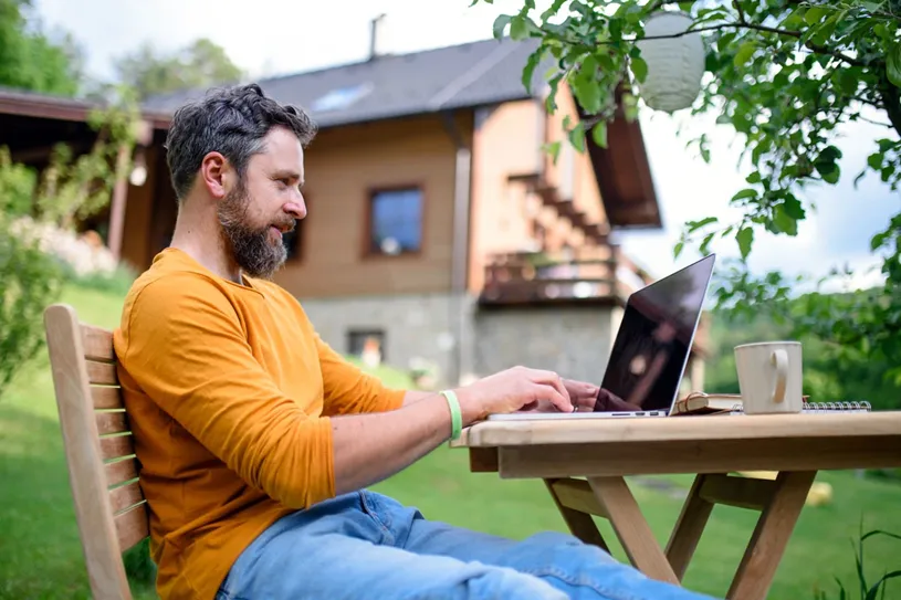 Side view of man with laptop learning outdoors in...
