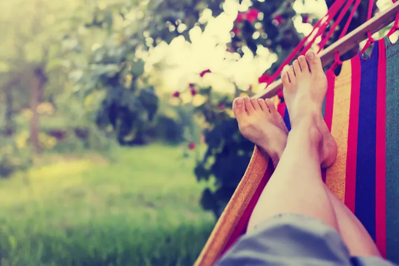 A person's feet resting comfortably in a hammock,...